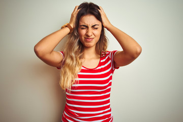 Fototapeta premium Young beautiful woman wearing red stripes t-shirt over white isolated background suffering from headache desperate and stressed because pain and migraine. Hands on head.