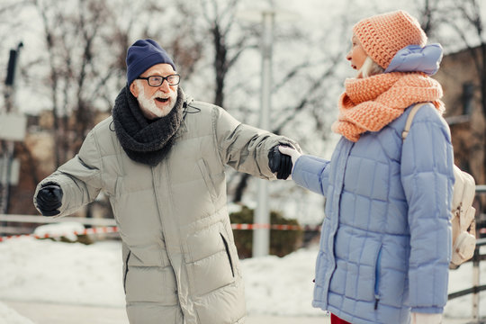 Excited aged man skating and wife holding his hand