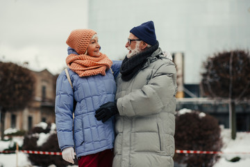 Aged couple in winter coats smiling and hugging