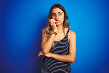 Young beautiful woman wearing stripes t-shirt over blue isolated background looking stressed and...