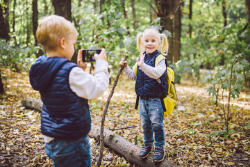 Children preschoolers Caucasian brother and sister take pictures of each other on mobile phone...