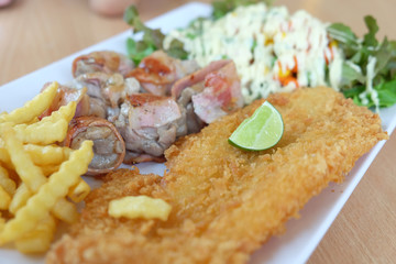 Fried fish and bacon served with french fries and salad