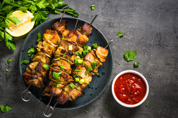 Grilled meat with herbs on black top view.
