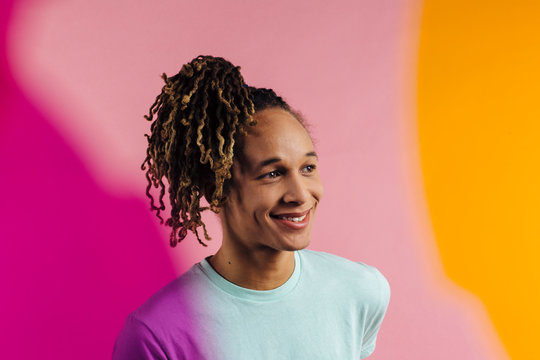 Colorful portrait of a smiling man with pony tail on pink