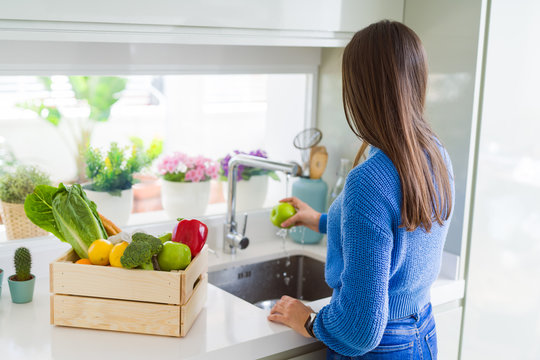 Young woman washing vegetables and fruit using water from sink
