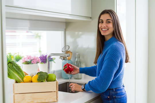 Young woman washing vegetables and fruit using water from sink