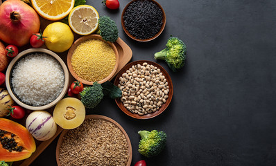 Bunch of fresh seasonal fruits, vegetables and grains of legumes on a black background