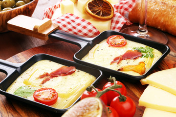Delicious traditional Swiss melted raclette cheese on diced boiled or baked potato and baguette served in individual skillets with salami..