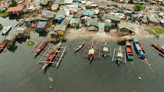 Slums with shacks of local residents and the river bank littered with garbage from above. Manila, Philippines.