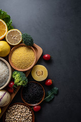 Bunch of fresh seasonal fruits, vegetables and grains of legumes on a black background