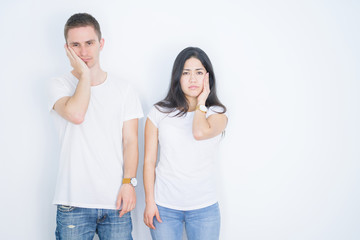 Young beautiful couple wearing casual t-shirt standing over isolated white background thinking looking tired and bored with depression problems with crossed arms.
