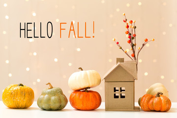 Hello fall message with collection of autumn pumpkins with a toy house