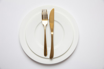 Table setting, formal. Gold cutlery on white set of dishes, white background