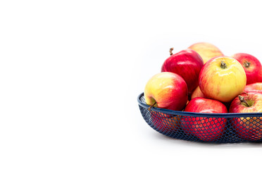 Red apples in a blue metal basket on a white background, front view, copy space.