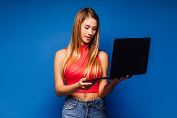 Gorgeous woman with laptop on hands searching information in blue background.