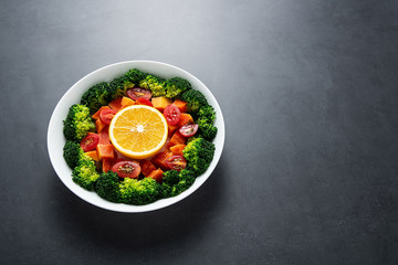 A plate of nutritious delicious fruit and vegetable salad on a black background