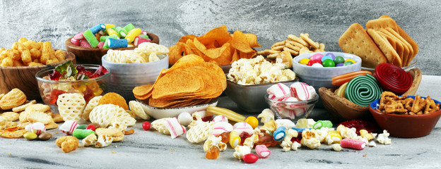 Salty snacks. Pretzels, chips, crackers and candy sweets on table