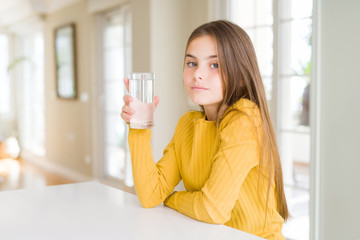 Beautiful young girl kid drinking a fresh glass of water with a confident expression on smart face thinking serious