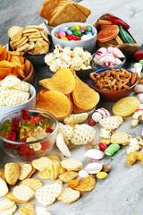 Salty snacks. Pretzels, chips, crackers and candy sweets on table