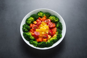 A plate of nutritious delicious fruit and vegetable salad on a black background