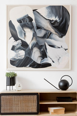 Interior design of living room at nice scandinavian apartment with stylish commode, abstract paintings, tropical plant, books and elegant accessories. Modern home decor. Template. Mock up. Minimalist.