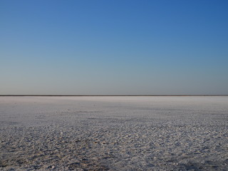 white surface of the lake covered with salt at sunrise