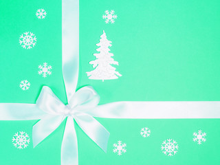 White bow, snowflakes, fir tree on a green background. Christmas and New Year concept