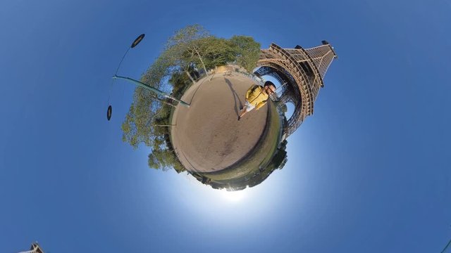 Little planet 360 degree sphere. A tourist visiting the Eiffel tower.