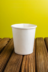 Empty cardboard cup on a bright yellow and rustic background
