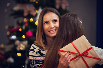 Mother and daughter with presents over Christmas tree