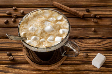 Cup of natural coffee with cinnamon, milk and marshmallows in morning