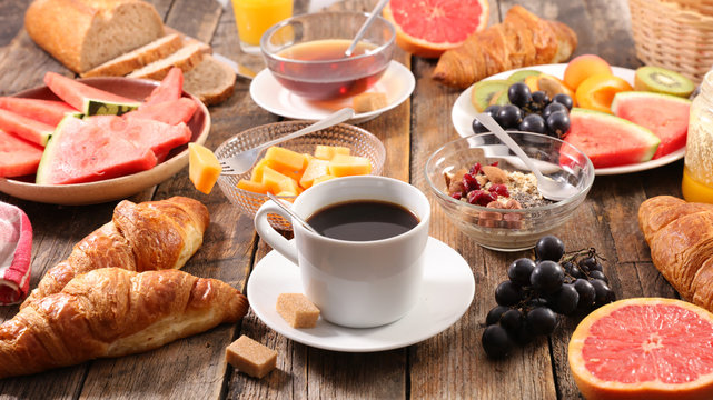 breakfast with coffee cup, tea cup, croissant and fruit