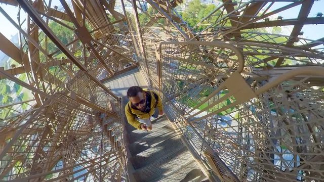 Tourist climbing to the top of Eiffel tower through the metallic stairs. Man POV.