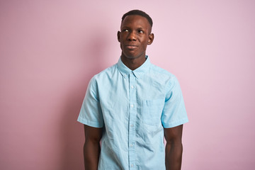 African american man wearing blue casual shirt standing over isolated pink background smiling looking to the side and staring away thinking.