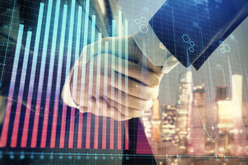 Double exposure of financial chart on cityscape background with two businessmen handshake. Concept of financial analysis and investment opportunities