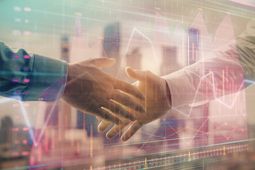 Double exposure of financial graph on cityscape background with two businessman handshake. Concept of stock market deal