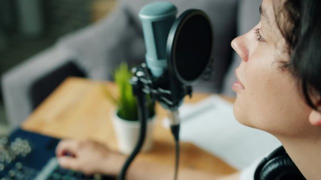 Close-up of handsome teenage boy talking in recording studio using equipment microphone and sound mixer sitting at table alone. People and technology concept.