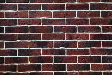 a wall of dark maroon brick with white putty