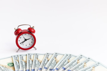 A concept about the relationship between time and money. An alarm clock and dollars bills.