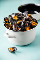 Pot full of steamed mussels on blue background