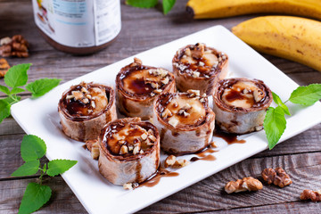 Delicious roll with banana slices on wooden background