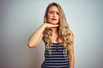 Fototapeta premium Young beautiful woman wearing stripes t-shirt standing over white isolated background cutting throat with hand as knife, threaten aggression with furious violence