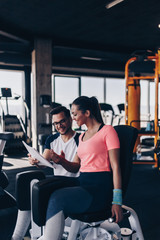 Young fit and attractive woman working out in modern gym together with her personal fitness instructor or coach.