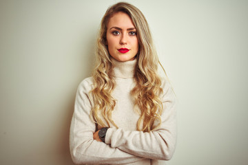 Beautiful woman wearing winter turtleneck sweater over isolated white background skeptic and nervous, disapproving expression on face with crossed arms. Negative person.