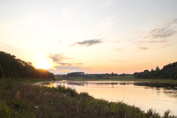 Naklejka na ściany i meble Sunset by the river in the summer countryside