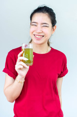 Woman in red shirt holding a glass of green tea and has a large smile