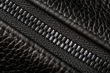 Close-up of the lock on a bag made of genuine black leather, on a dark background