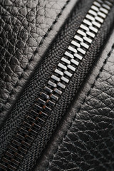 Close-up of the lock on a bag made of genuine black leather, on a dark background