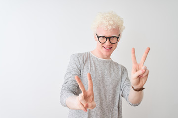 Young albino blond man wearing striped t-shirt and glasses over isolated white background smiling...