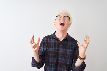 Young albino blond man wearing casual shirt and glasses over isolated white background crazy and...